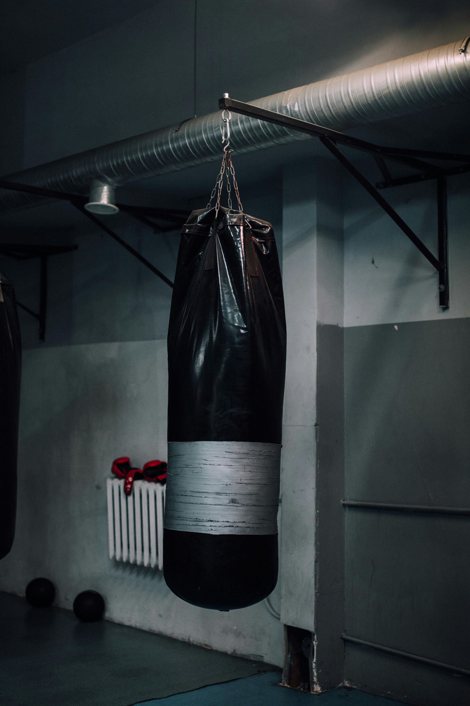 A boxing bag is hanging from the ceiling in a gym.