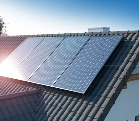 The sun is shining through the solar panels on the roof of a house.