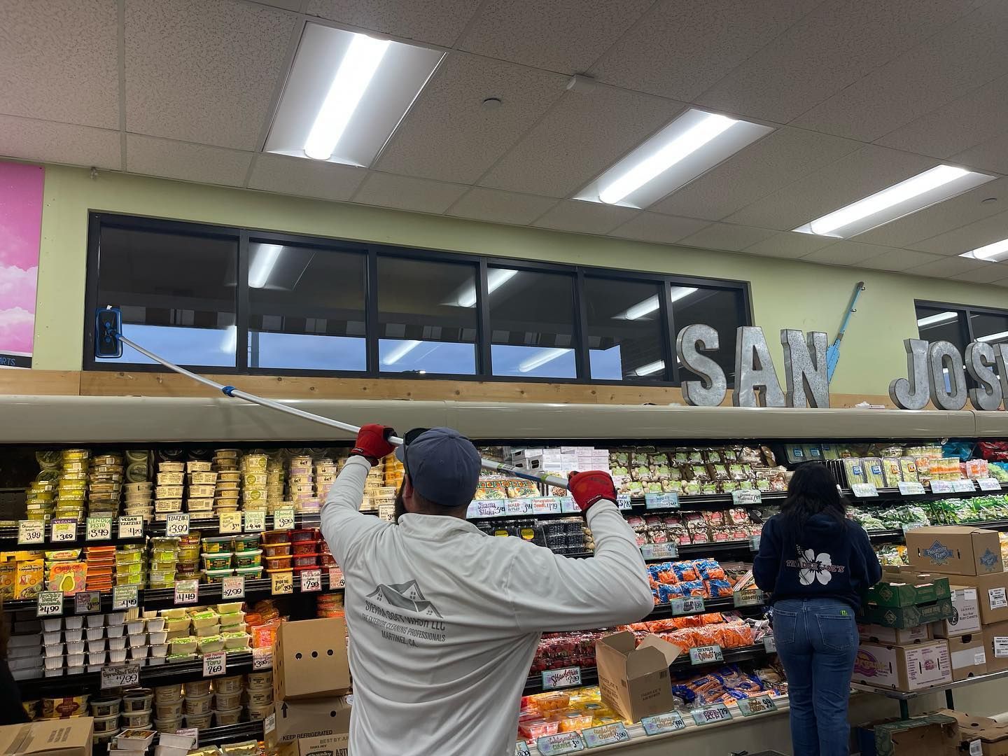 A man is cleaning a refrigerator in a grocery store