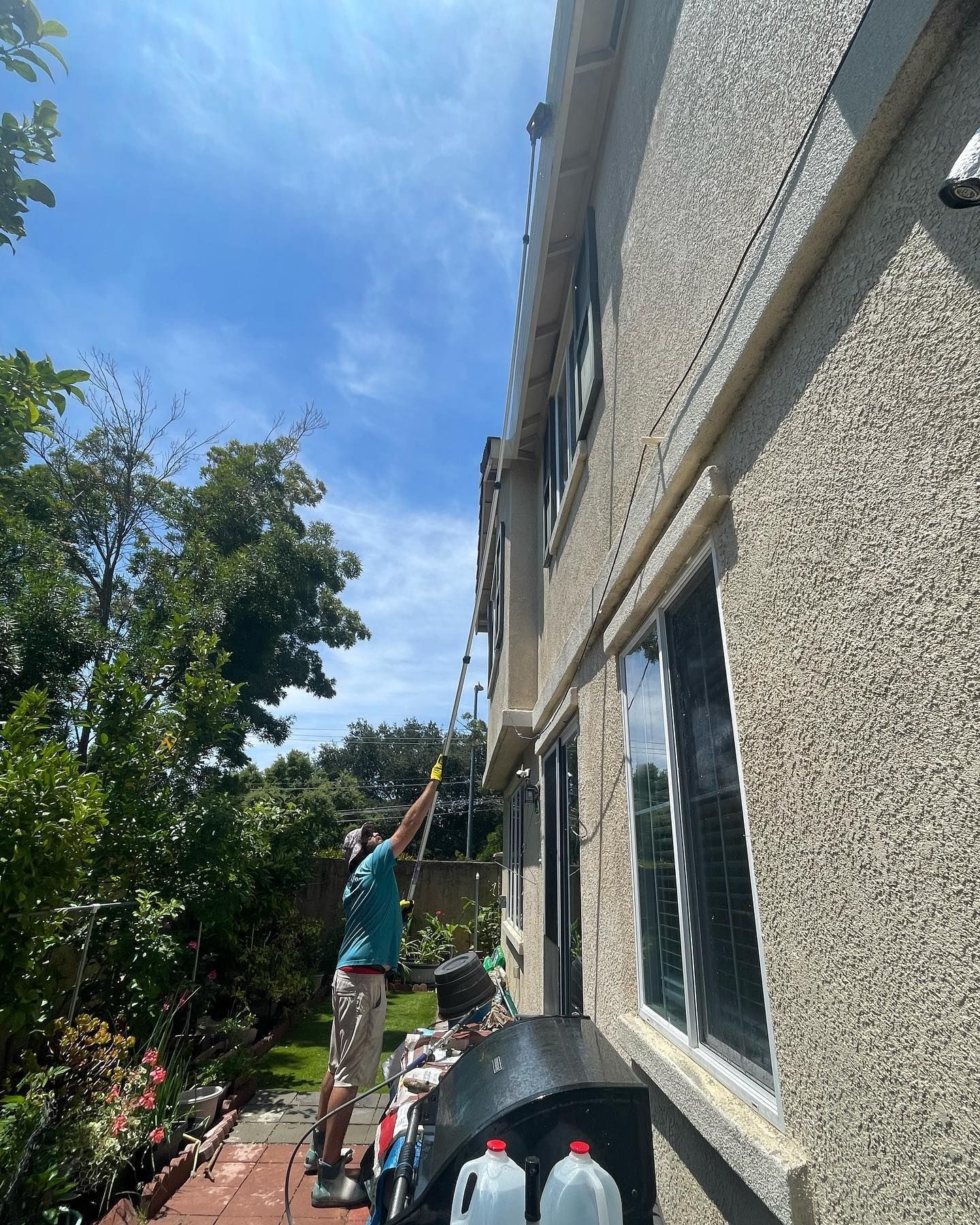 A man is cleaning the side of a building with a hose.