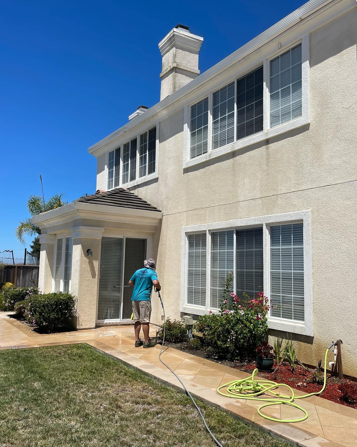 A man is cleaning the side of a house with a hose.