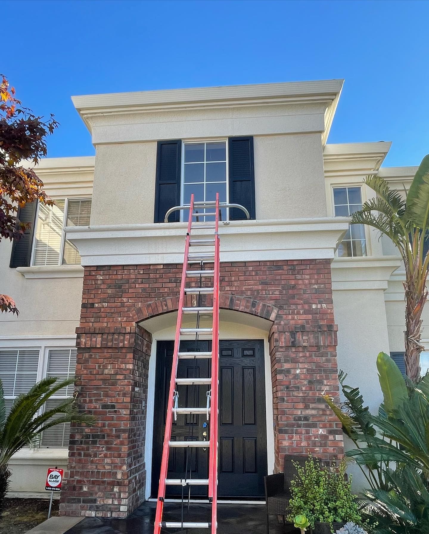 A ladder is sitting on top of a brick house.