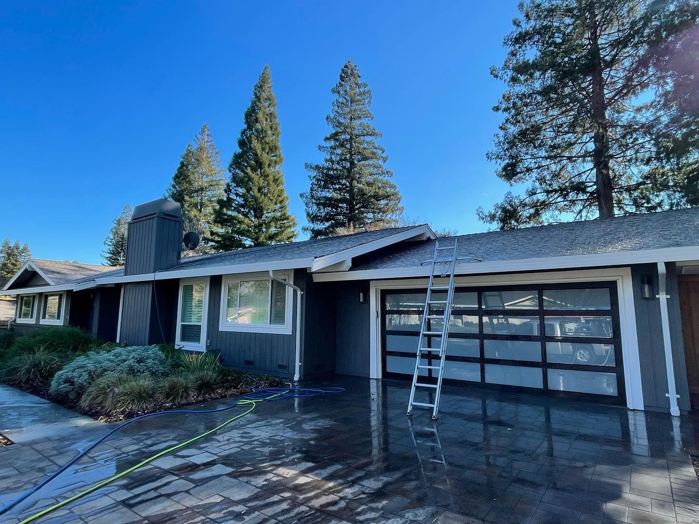 A house with a garage door and a ladder in front of it.