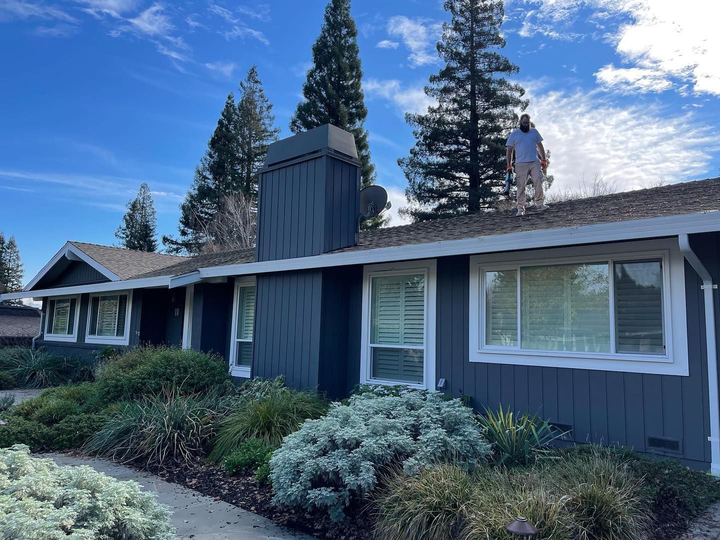 A man is standing on the roof of a house.