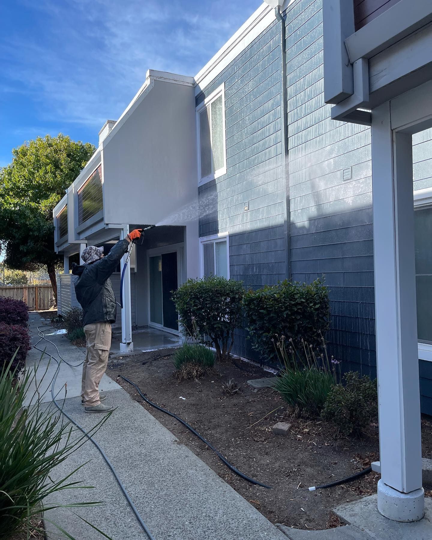 A man is spraying paint on the side of a building.
