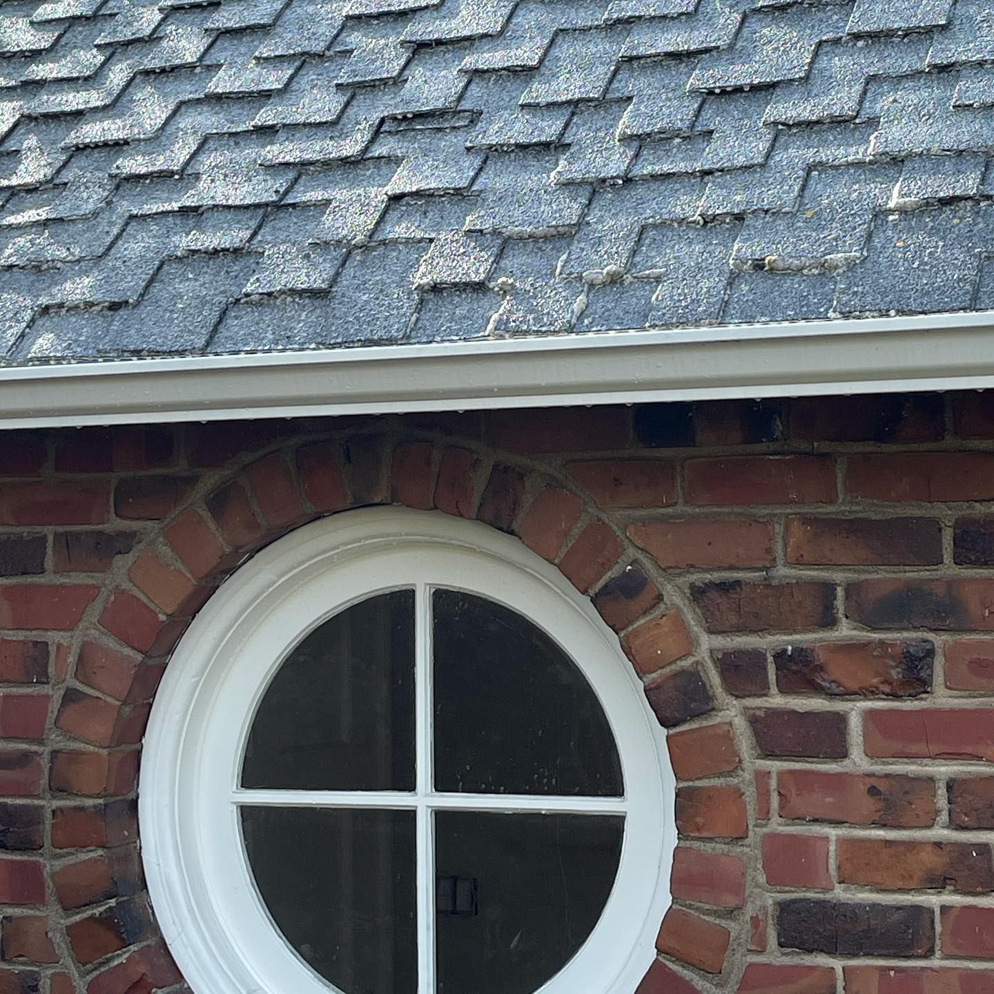 A brick building with a round window and a roof