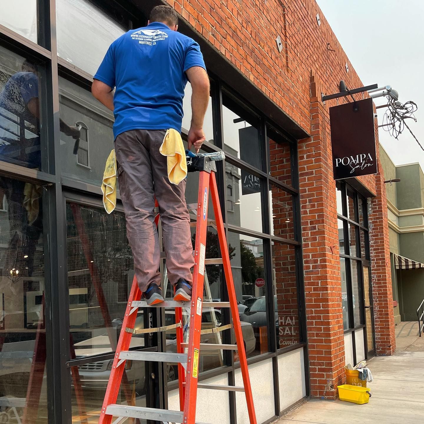 A man standing on a ladder in front of a building that says poppy