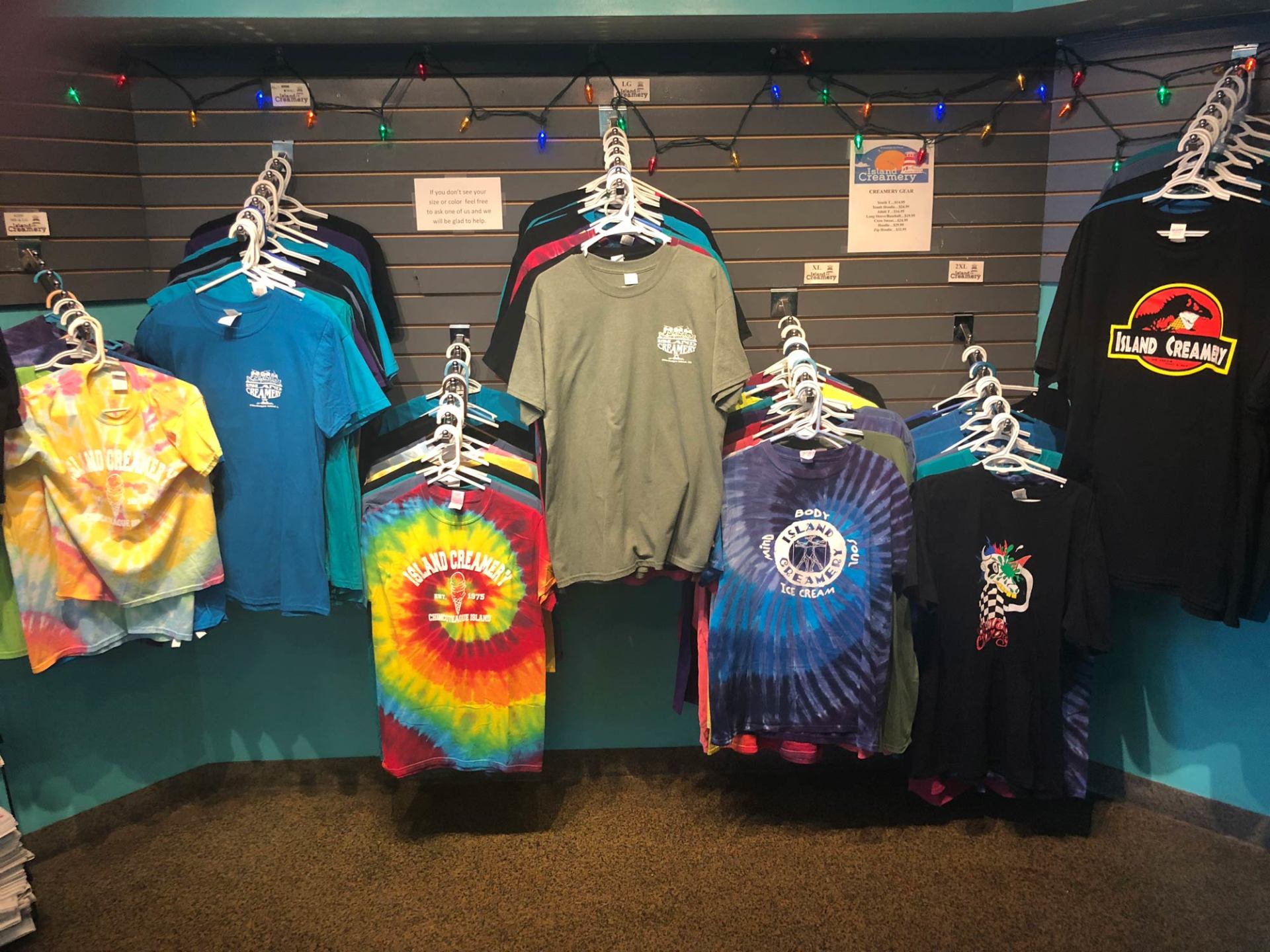 An assortment of t-shirts are hanging on a wall in a Island Creamery.