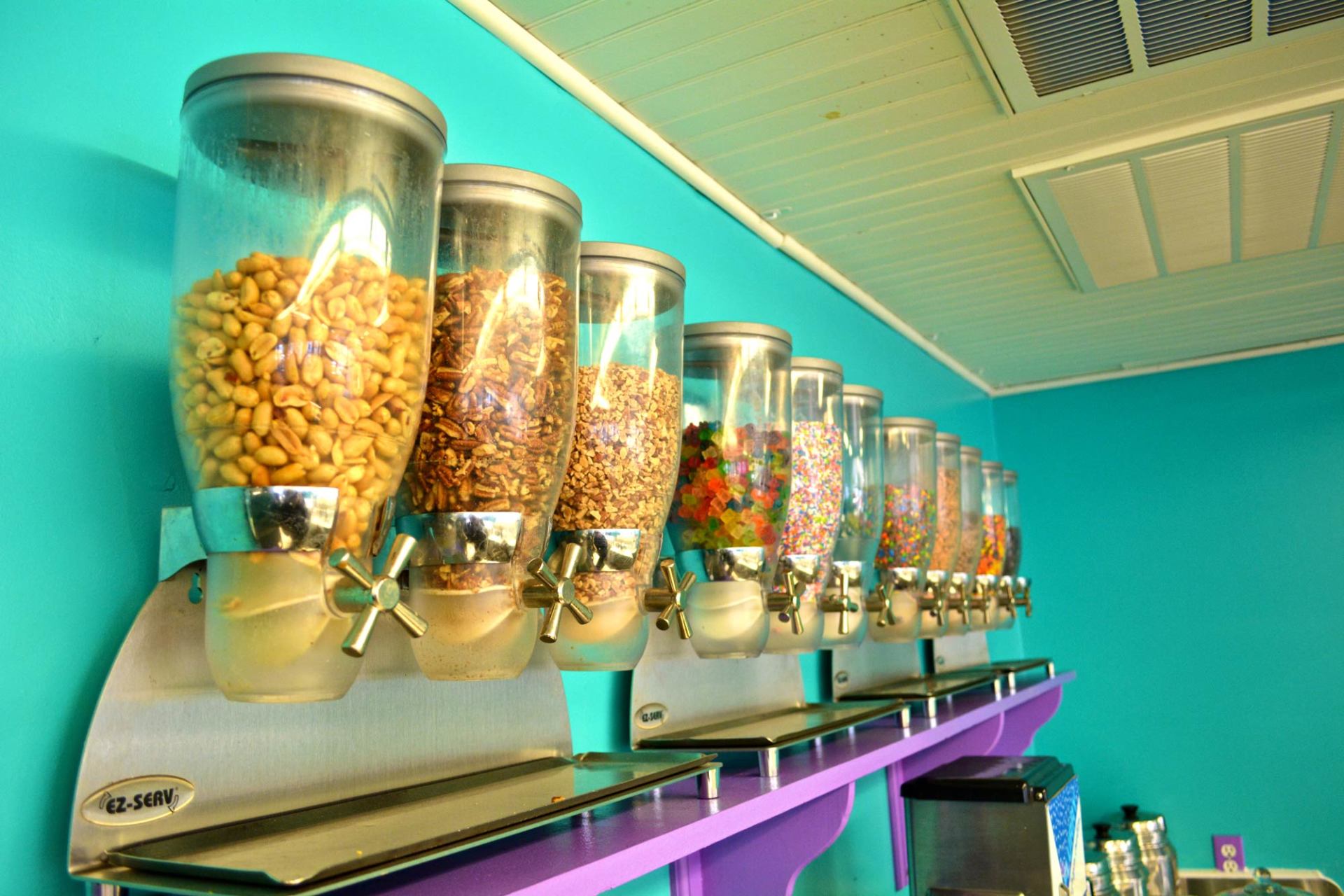 A row of candy dispensers are lined up on a shelf in Island Creamery.