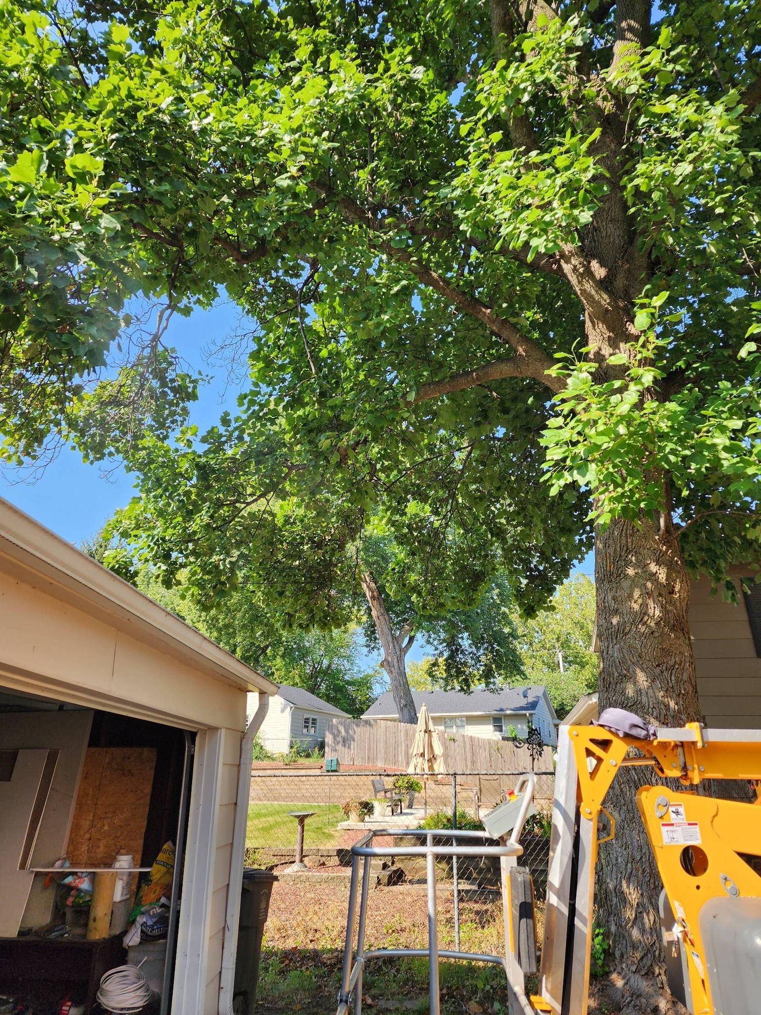 A tree is being cut down in front of a garage.