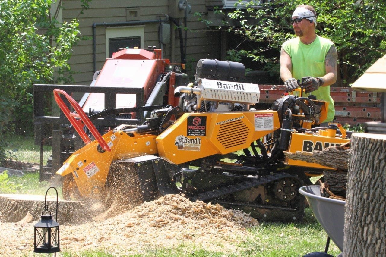 A man is using a machine to remove a tree stump.