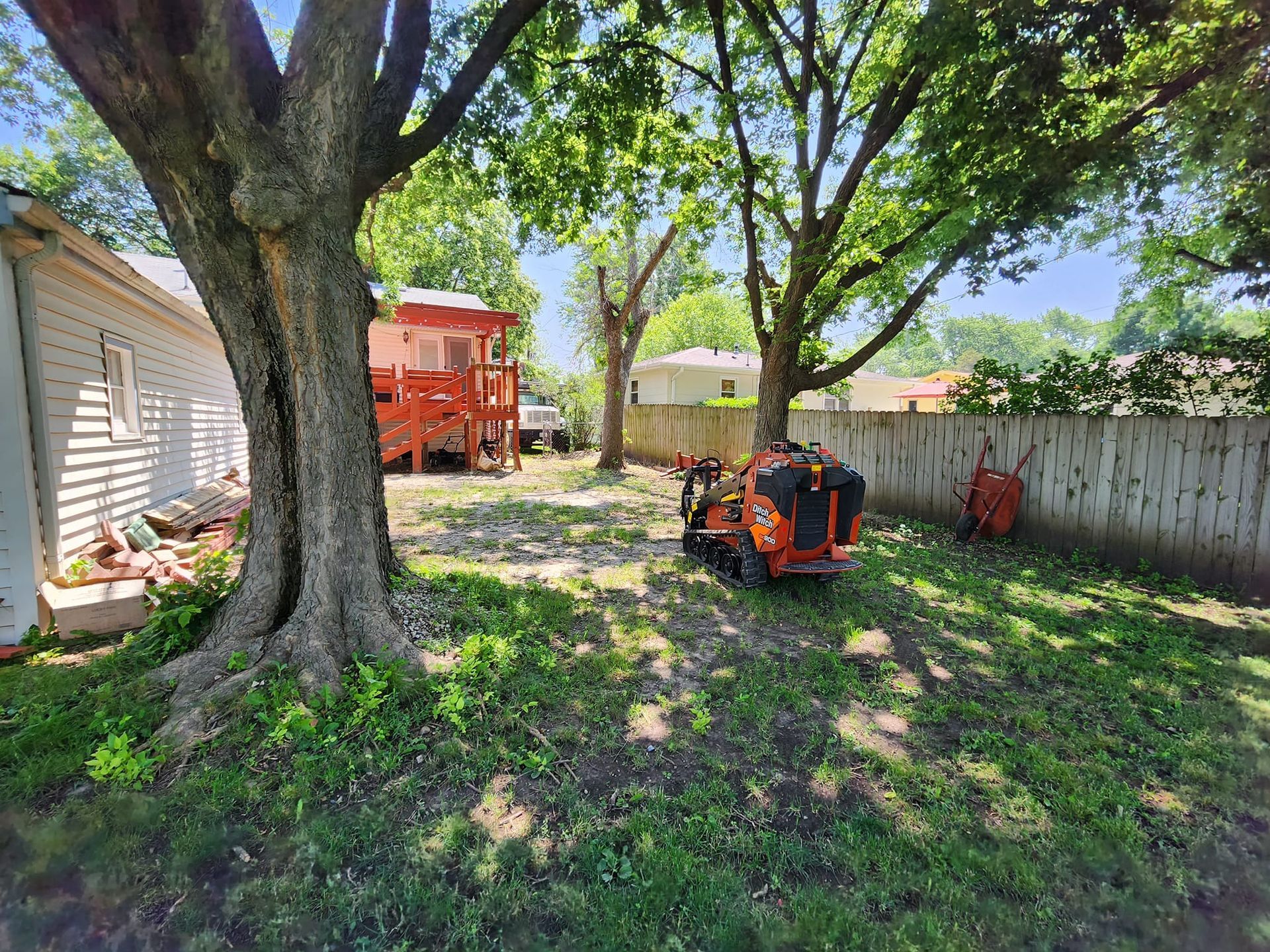 A lawn mower is parked in a backyard next to a tree.