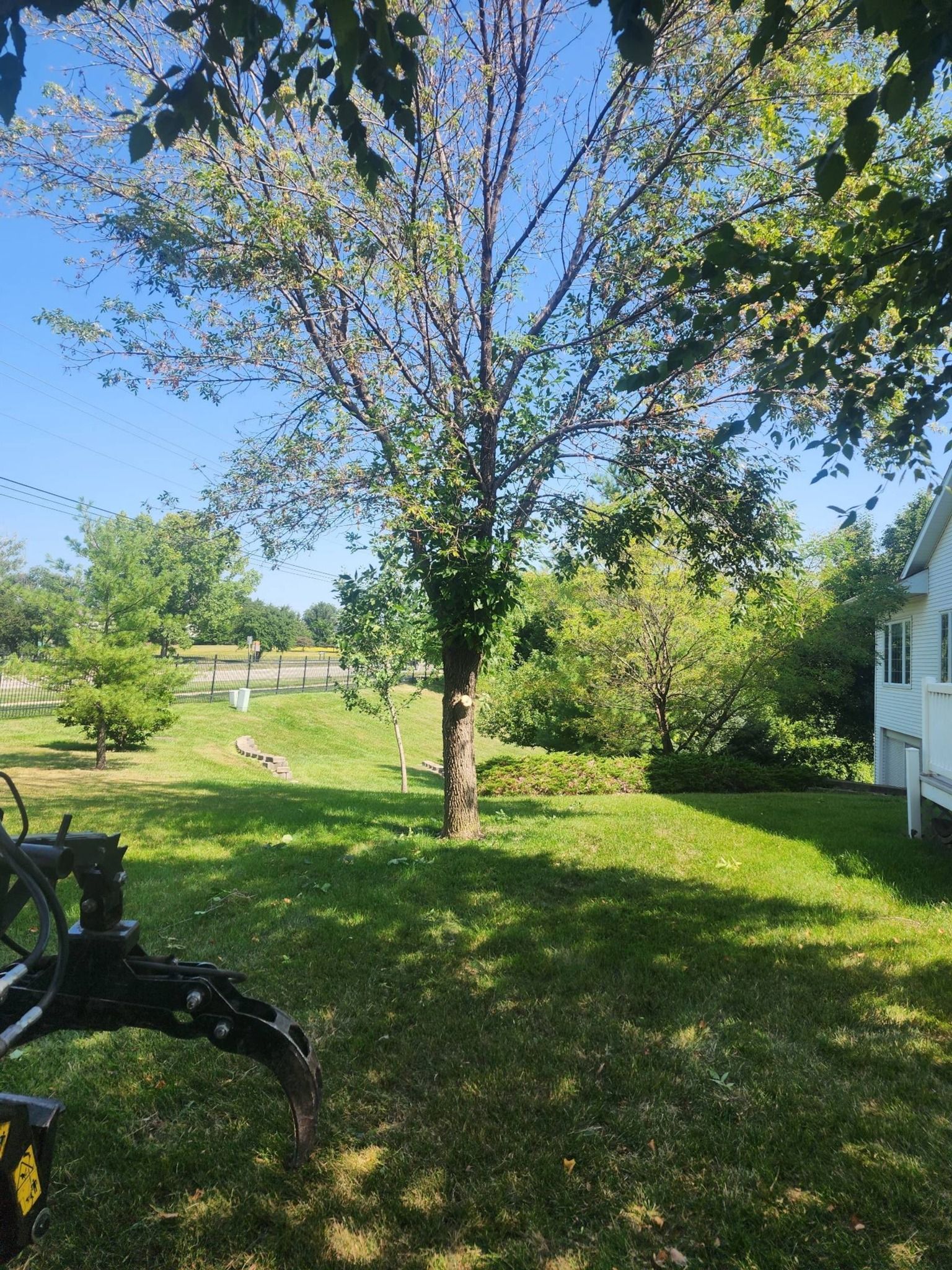 A lawn mower is sitting in the grass in front of a house.
