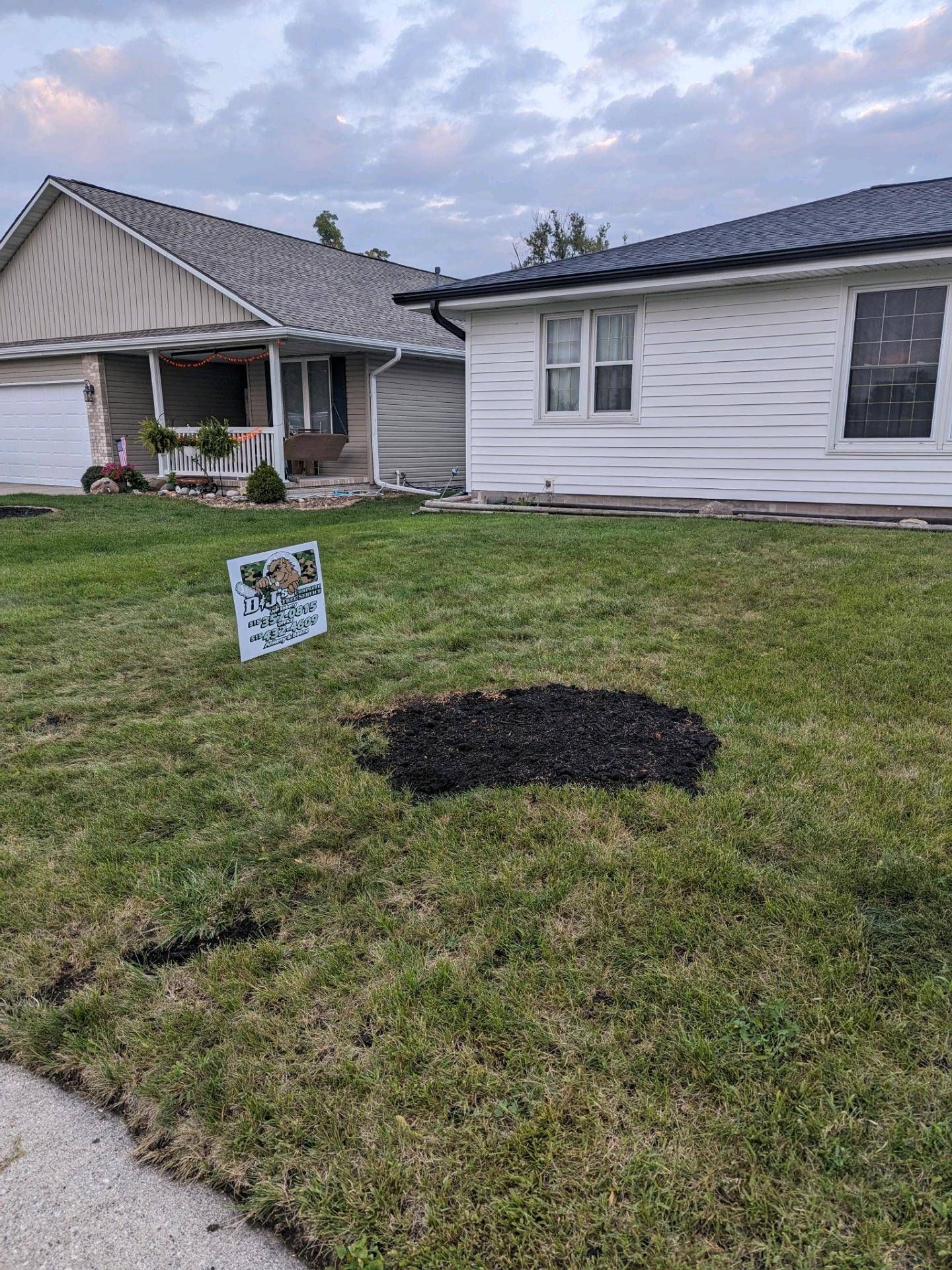 There is a hole in the grass in front of a house.