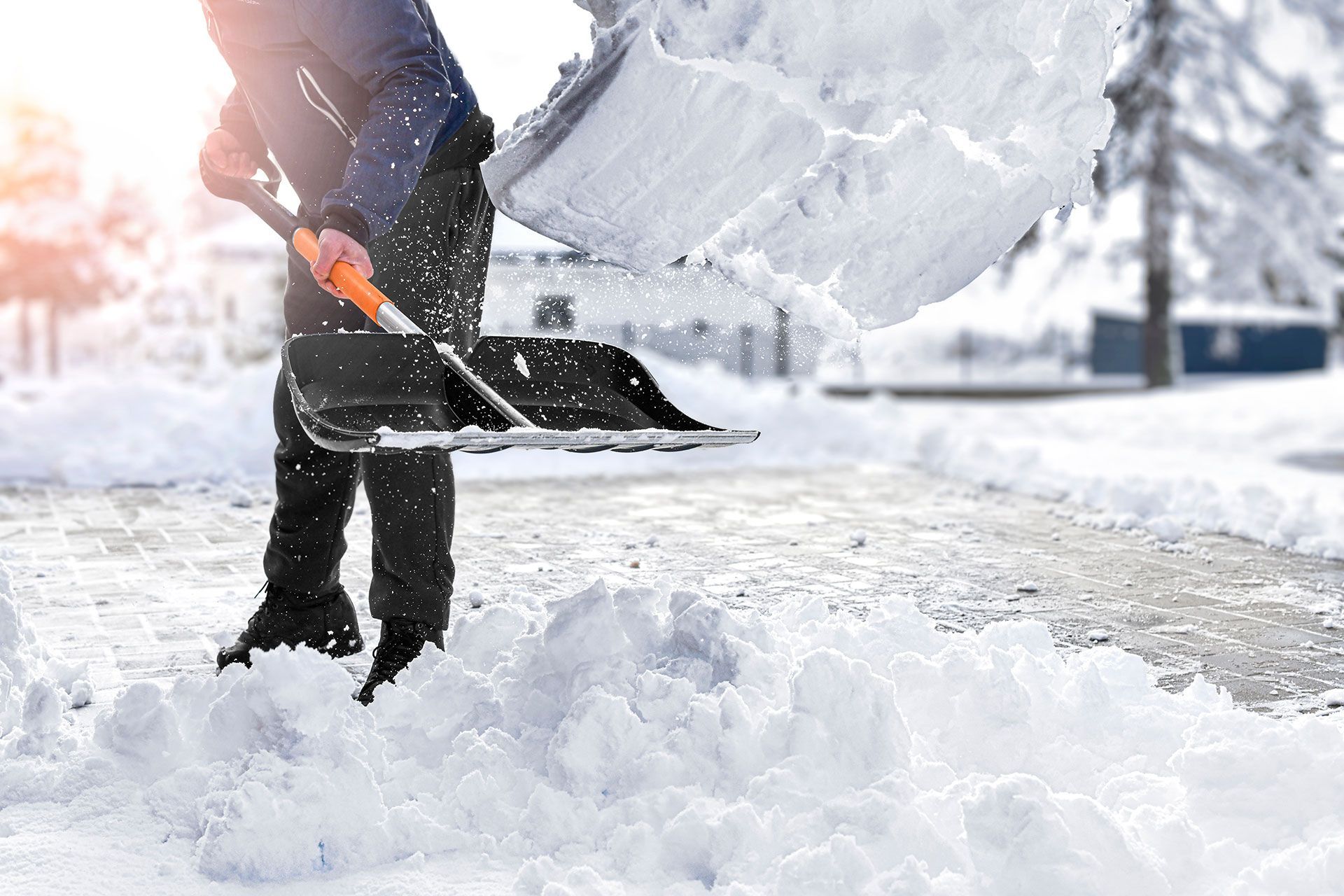 A person is shoveling snow from a sidewalk with a shovel.