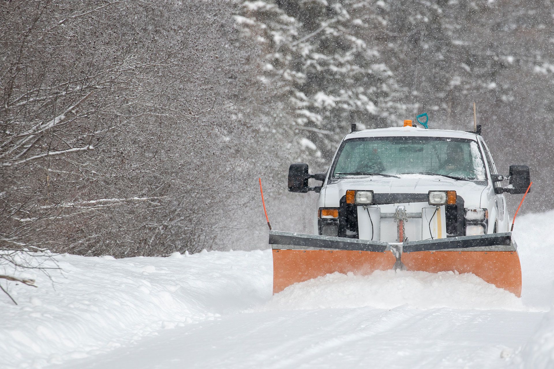 A snow plow is plowing snow on a snowy road.