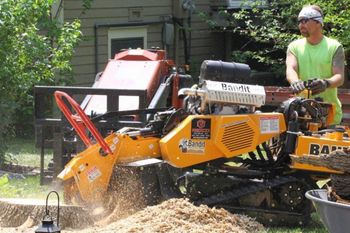 A man is using a machine to remove a tree stump.