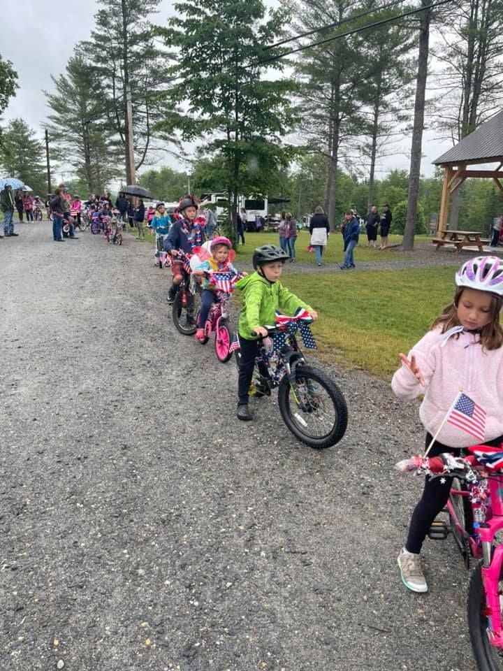 A group of children are riding bicycles down a dirt road.