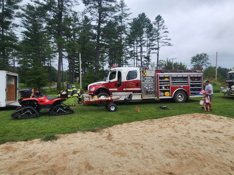 A red and white fire truck is parked in a grassy field.