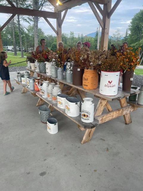 A picnic table filled with buckets and vases of flowers.