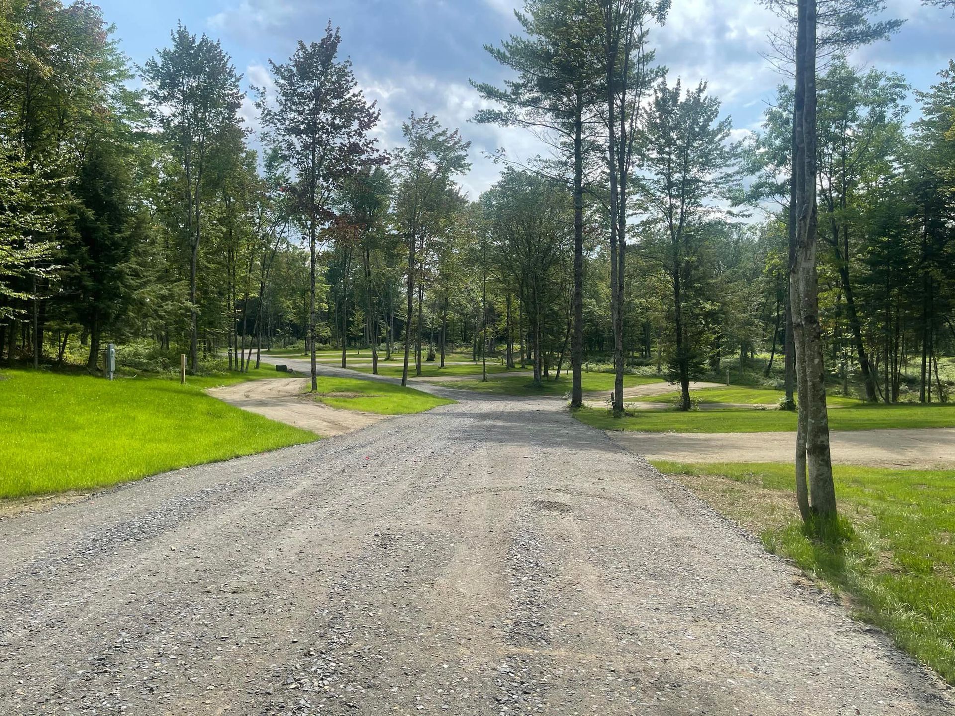 A dirt road going through Kingdom Campground with trees on both sides.
