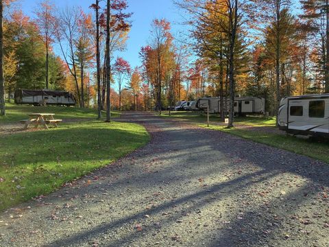 A gravel road leading to a campground filled with RVs and a picnic table.
