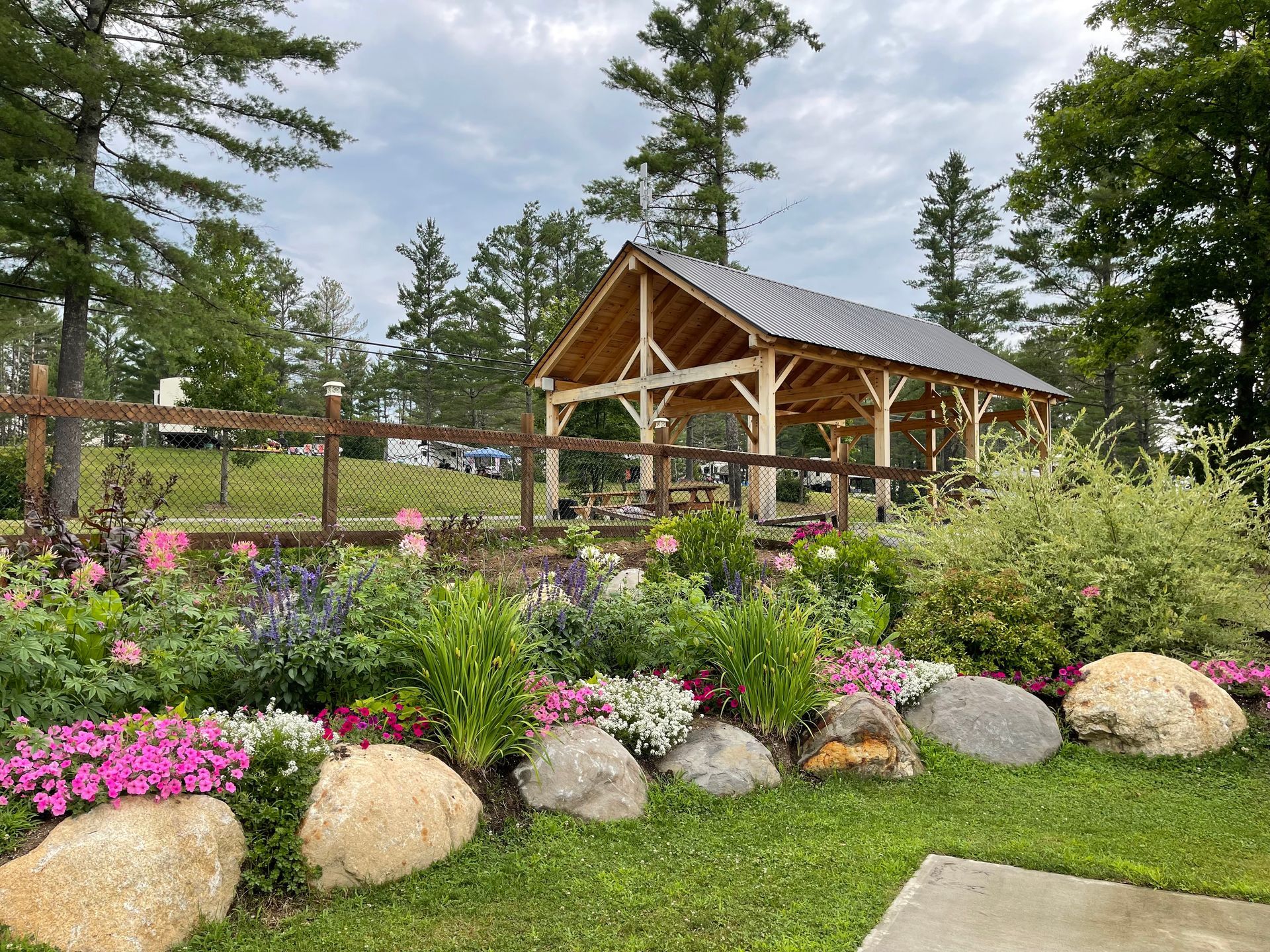 A gazebo is surrounded by flowers and rocks in a garden.