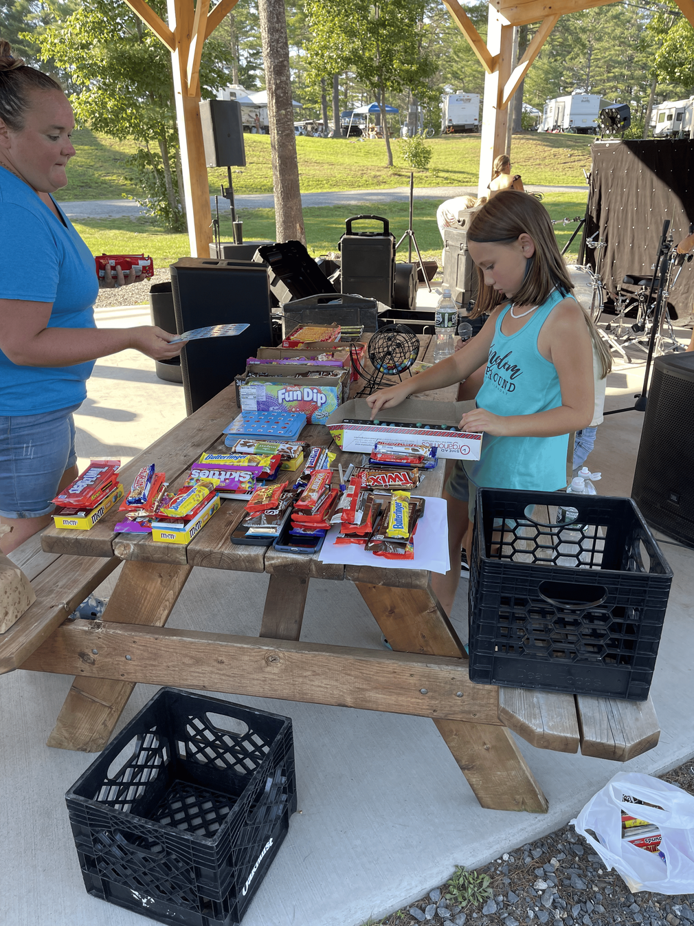 A woman and a girl are standing at a picnic table.