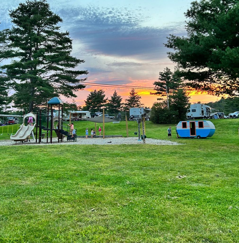 A playground in the campground with a sunset in the background