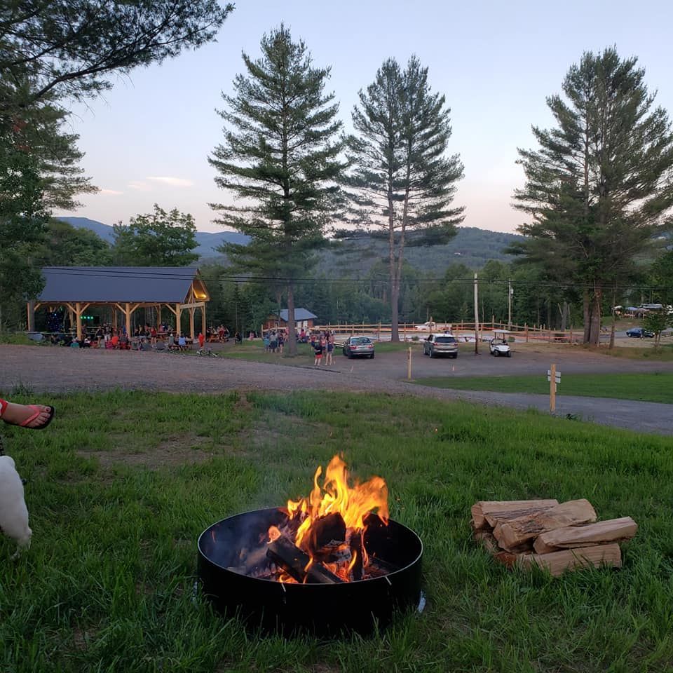 A fire pit at a campsite looking down to the pavilion