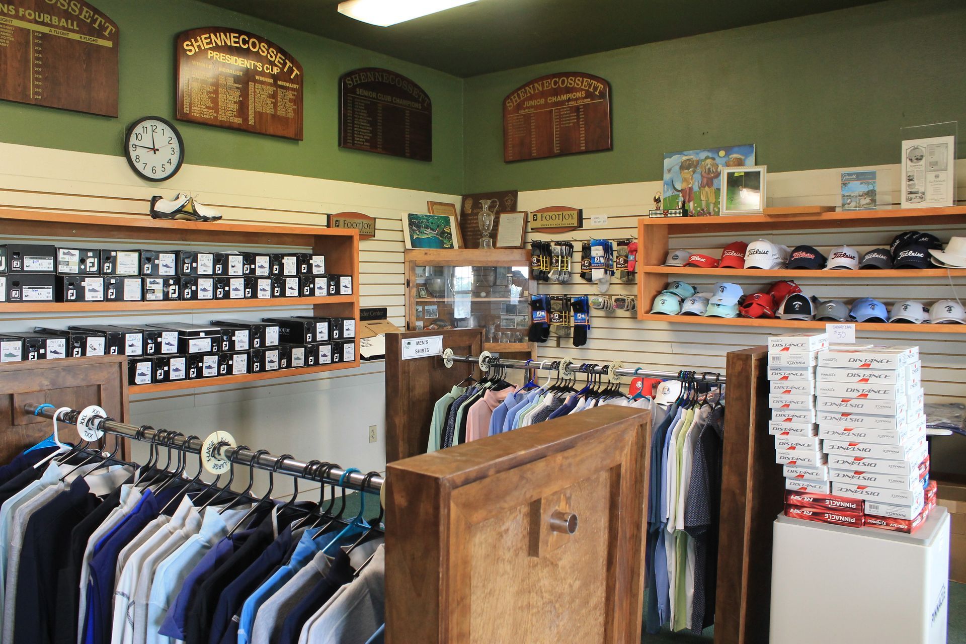 Clothing store interior with racks of shirts, shelves of folded items, and framed wall decor