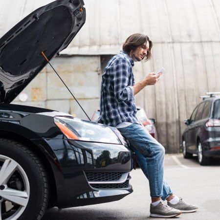 man leaning on car looking for car insurance