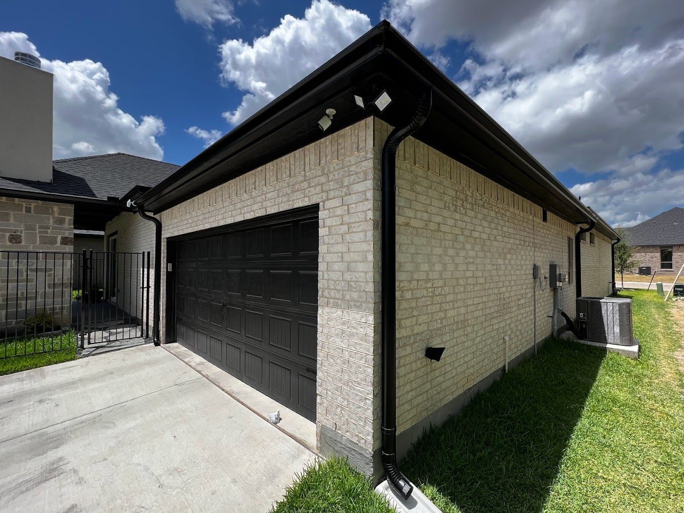 A white brick house with a black garage door.