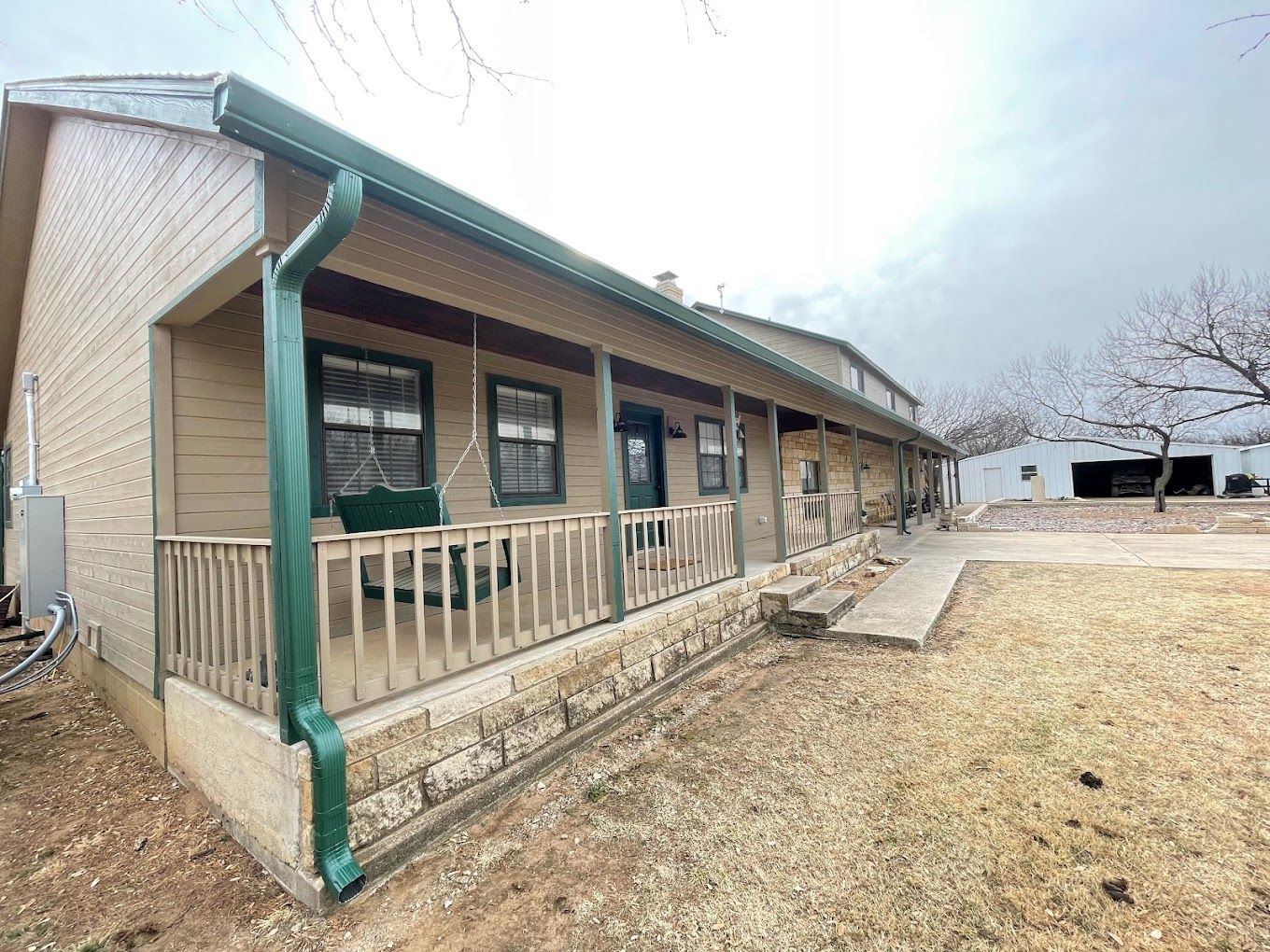 A large house with a large porch and a green gutter.