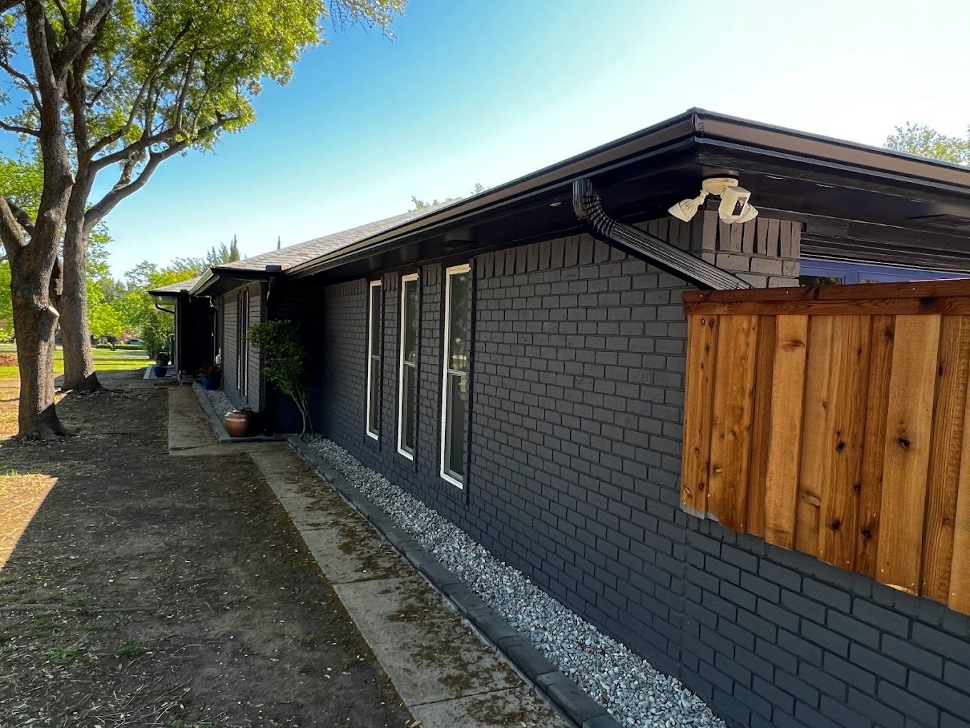 A black brick house with a wooden fence in front of it