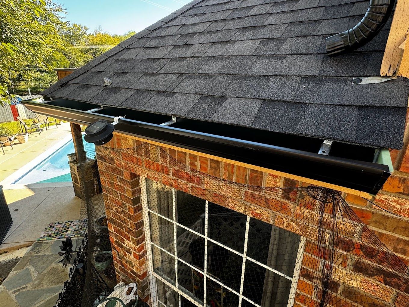 A brick building with a black roof and a window.