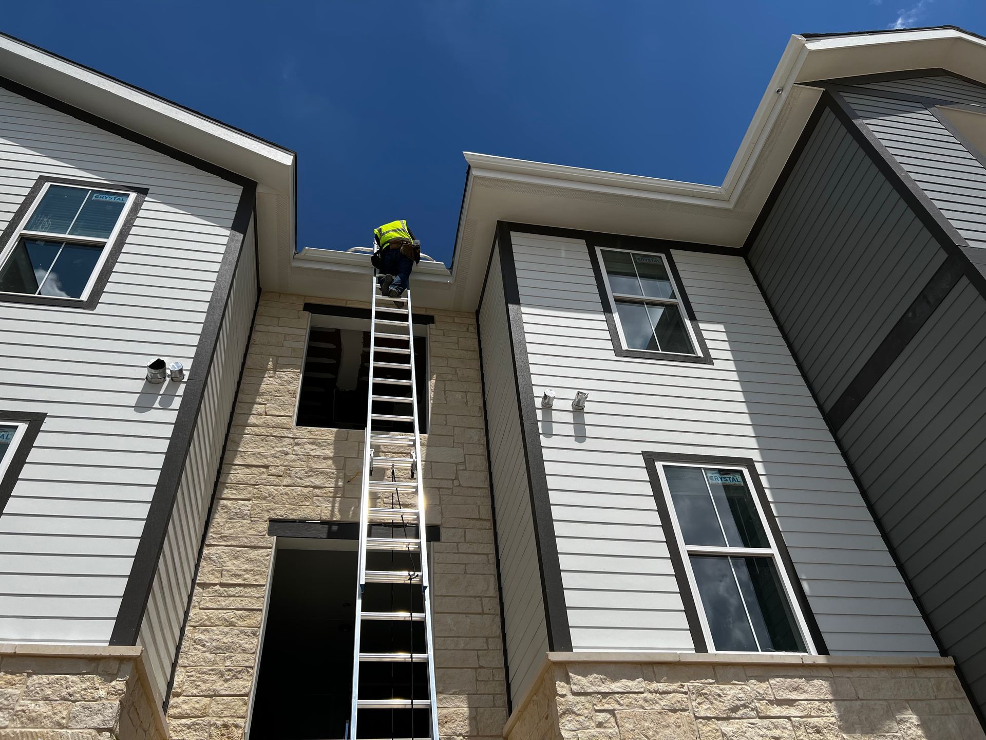 A man on a ladder cleaning the roof of a building