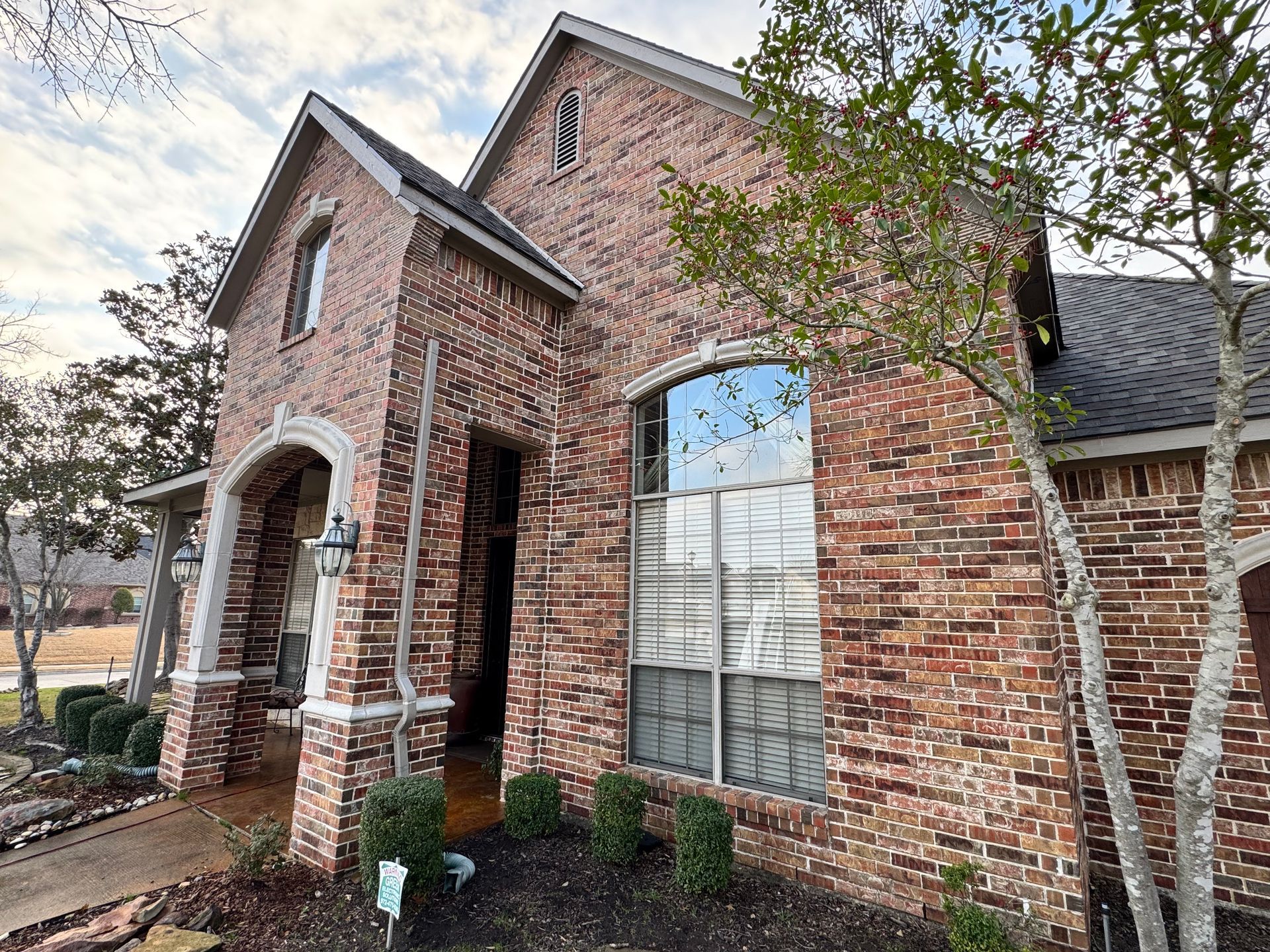 A large brick house with a lot of windows and trees in front of it.