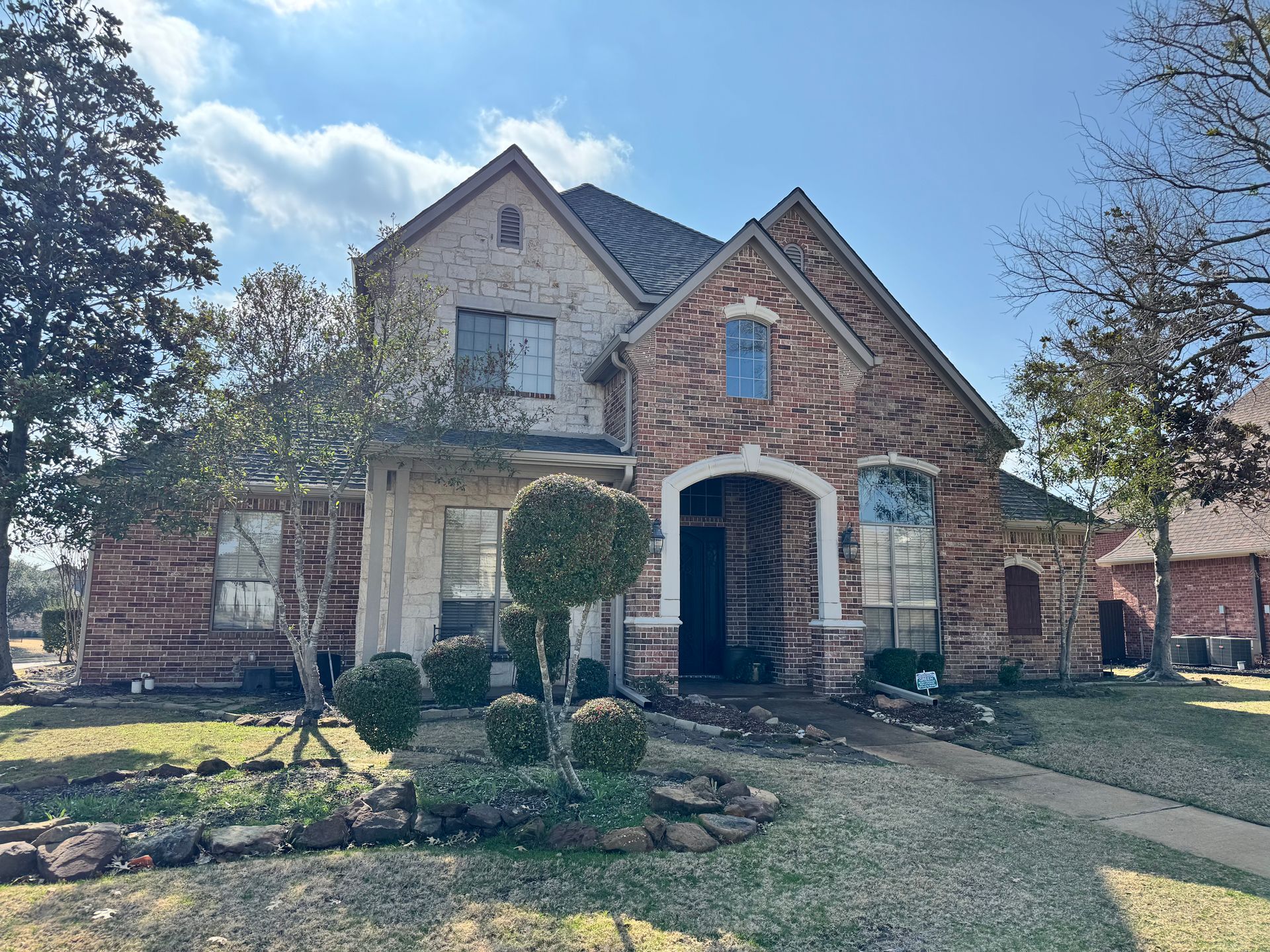 A large brick house with a roof that is covered in shingles.