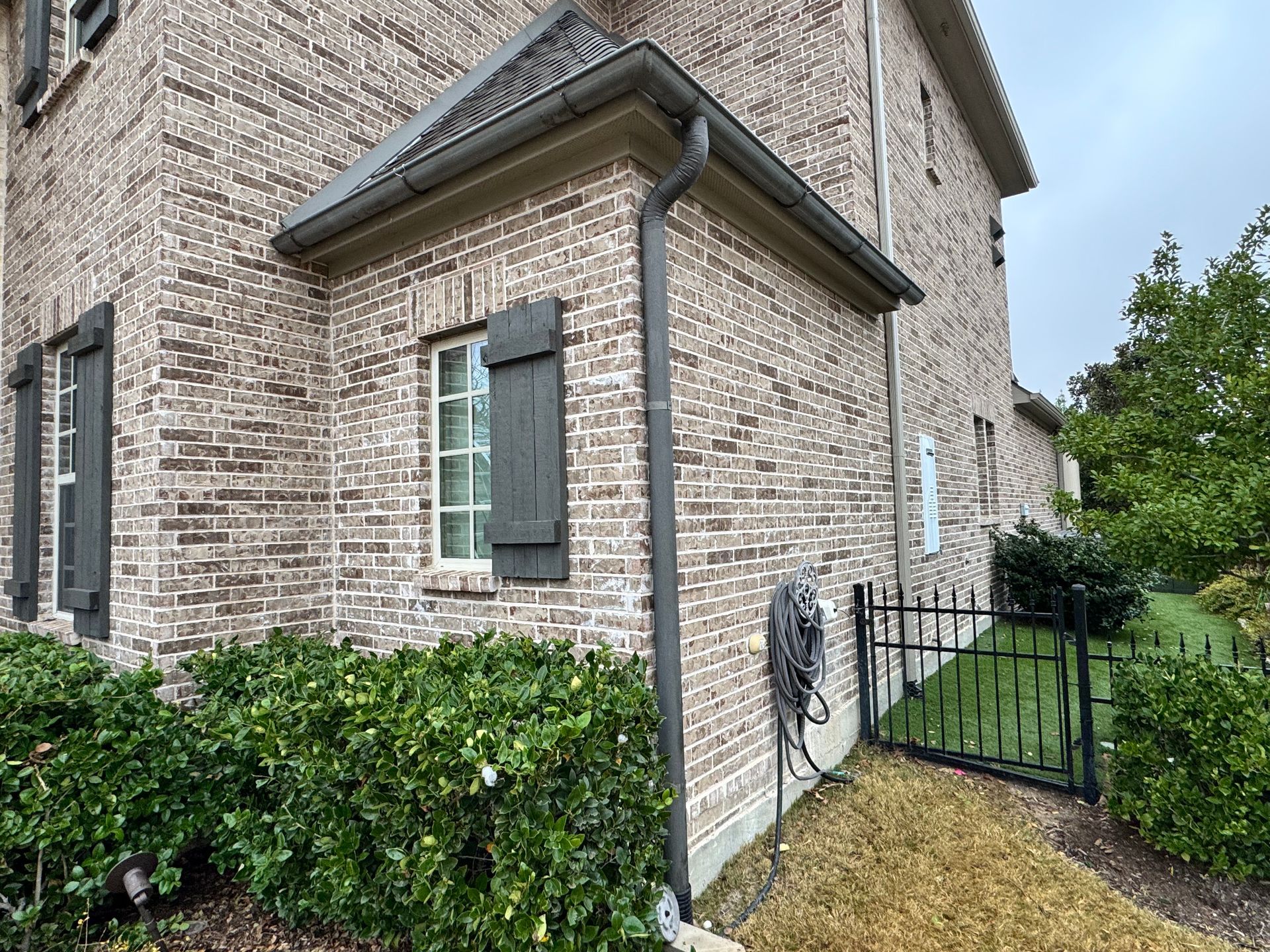 A white gutter is attached to the roof of a house.
