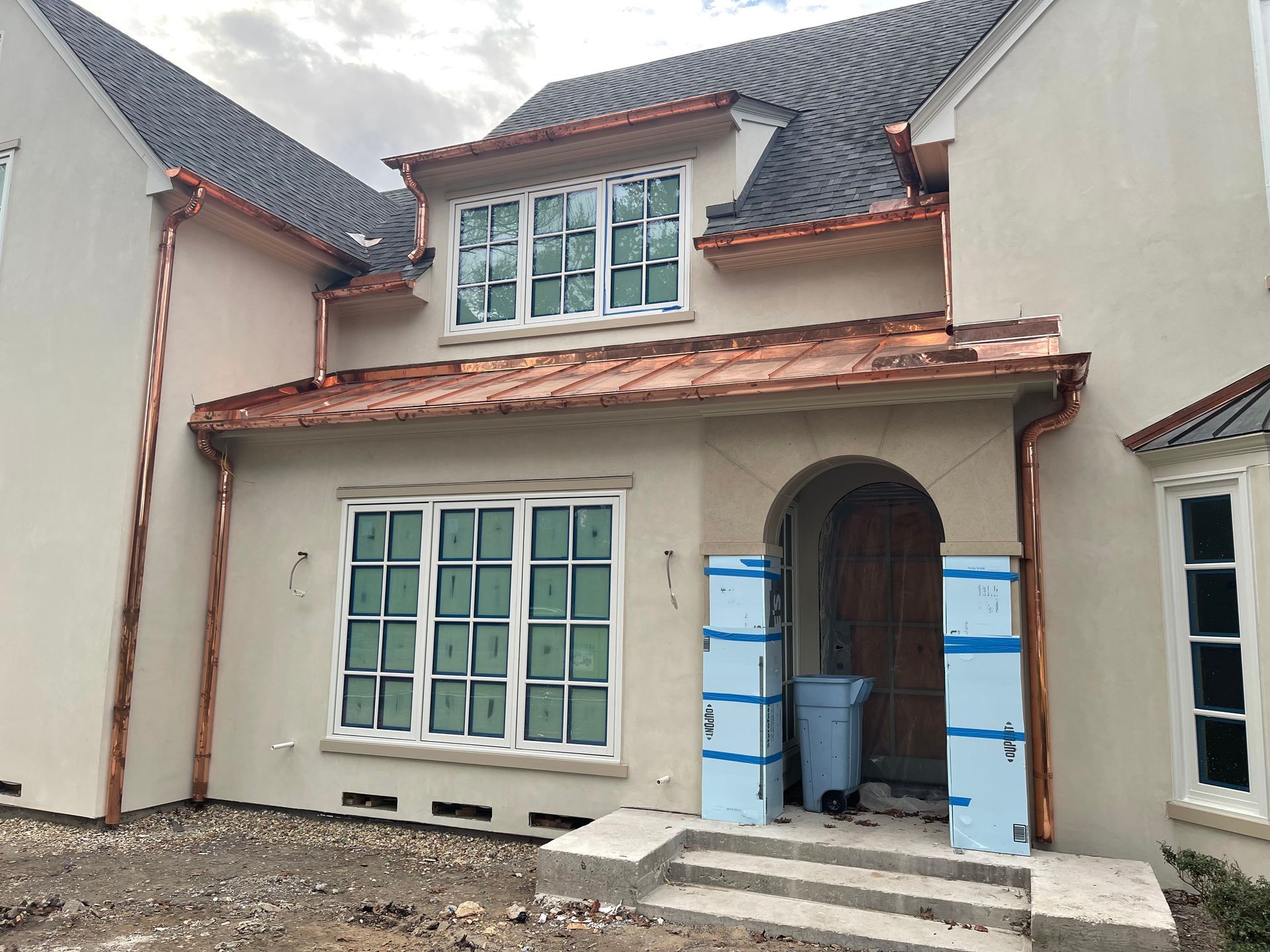 A house with copper gutters and windows is being built.