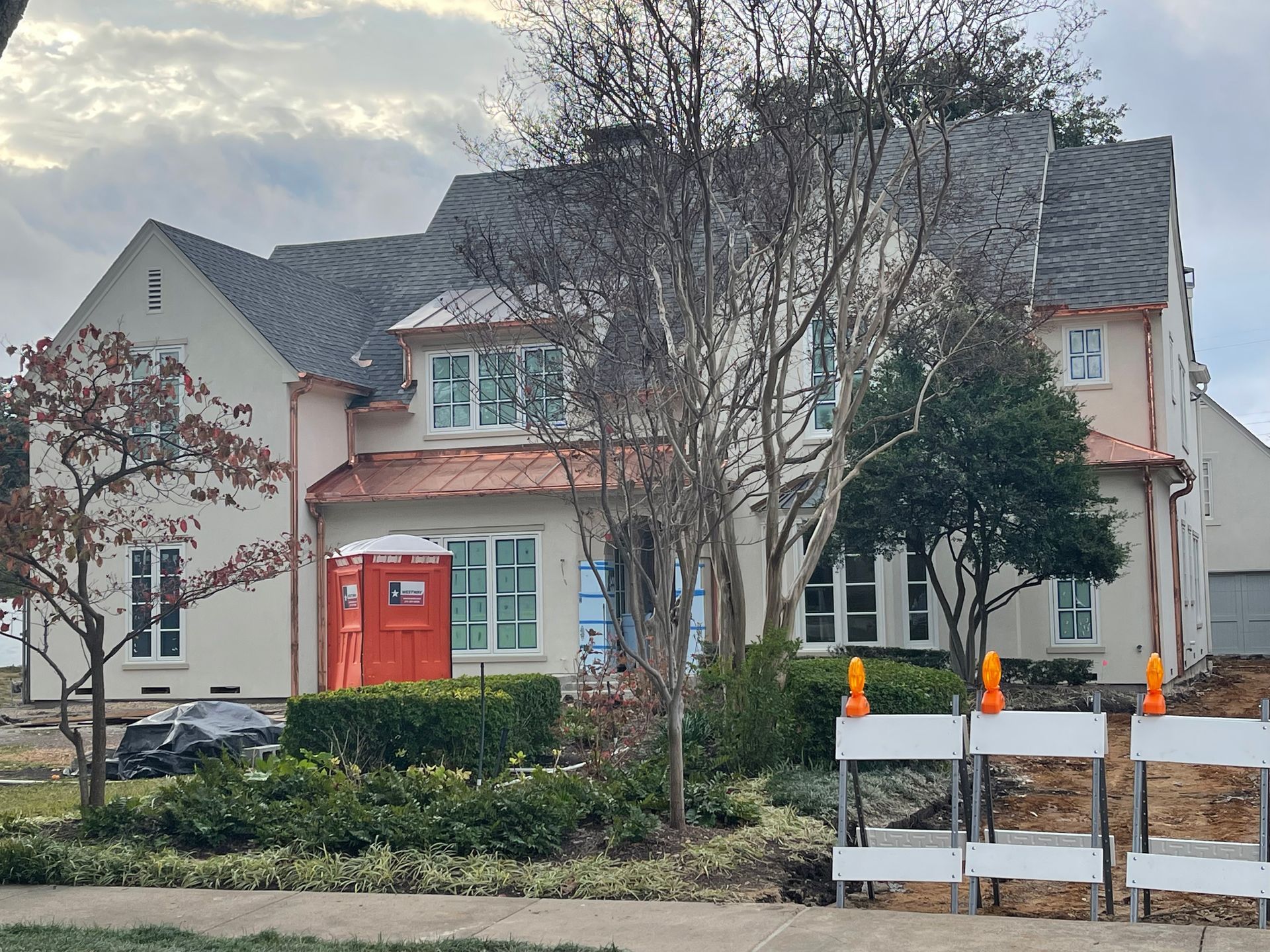 A large white house with a copper roof and a red door
