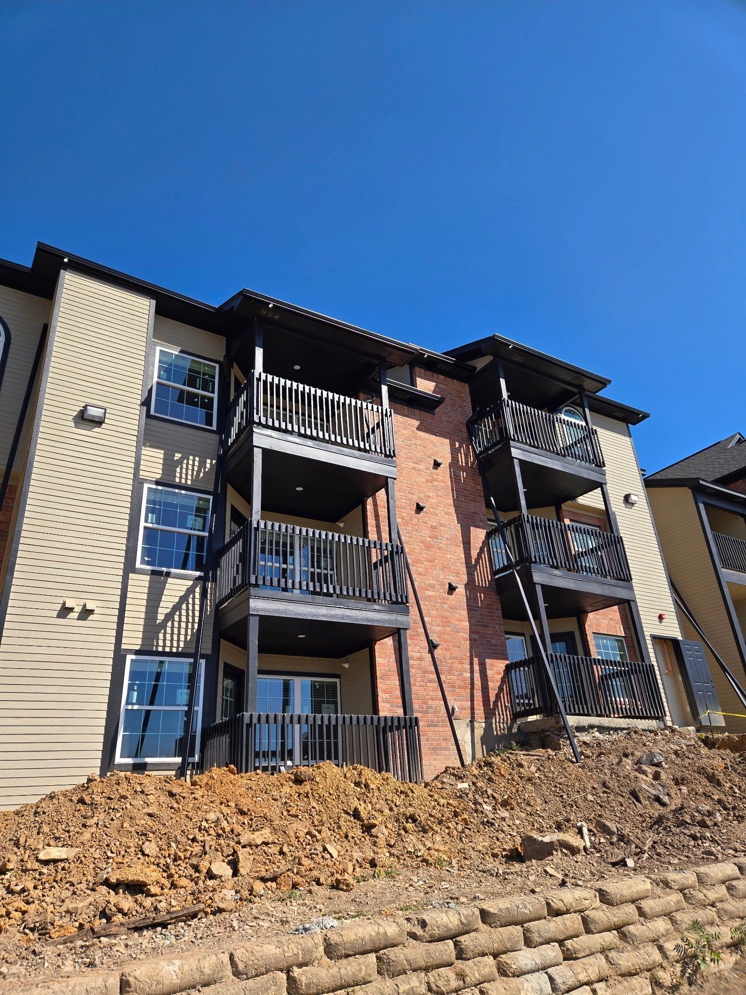 A large apartment building with stairs and balconies is sitting on top of a hill.