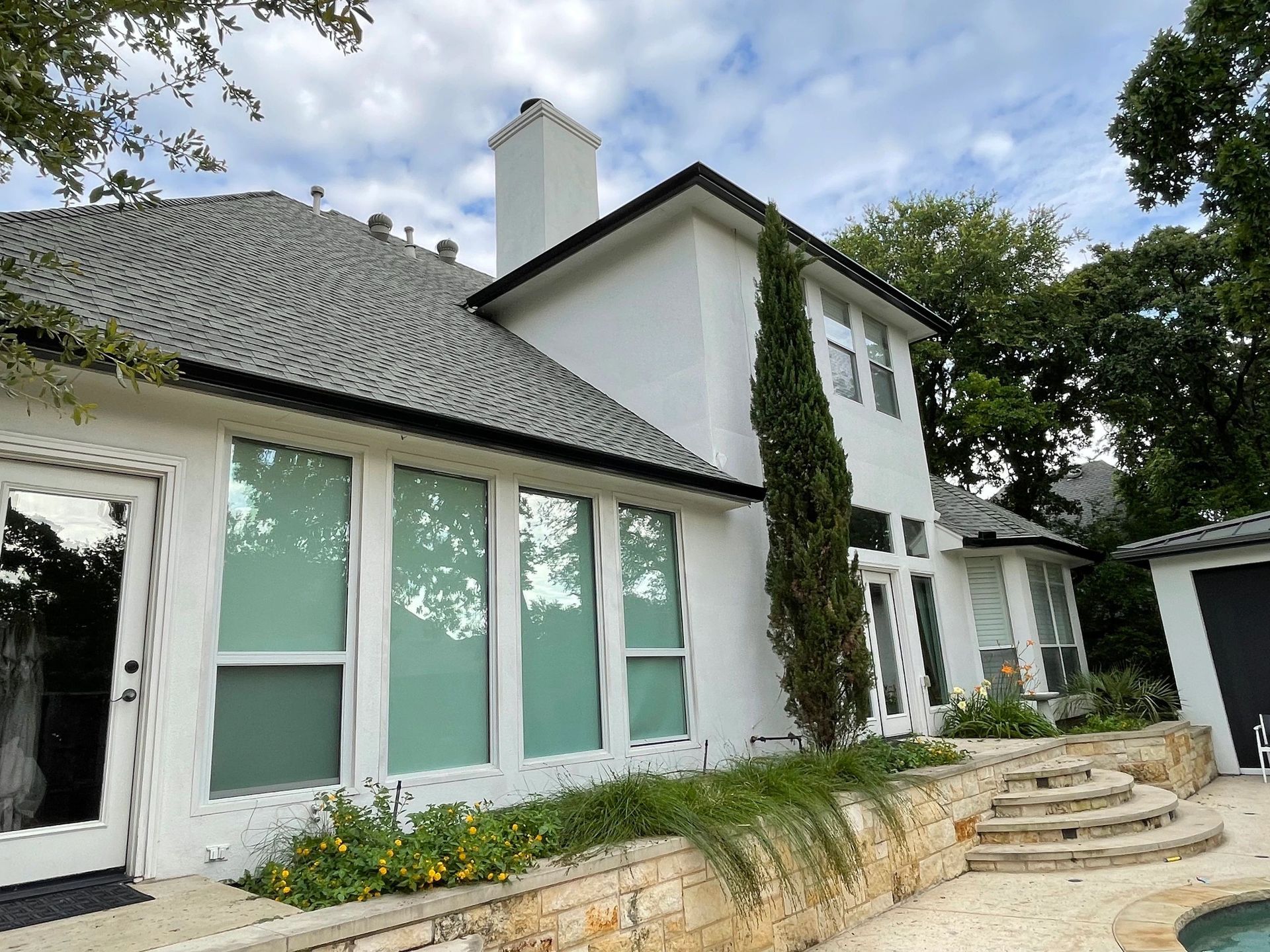 A large white house with a gray roof and a pool in the backyard.