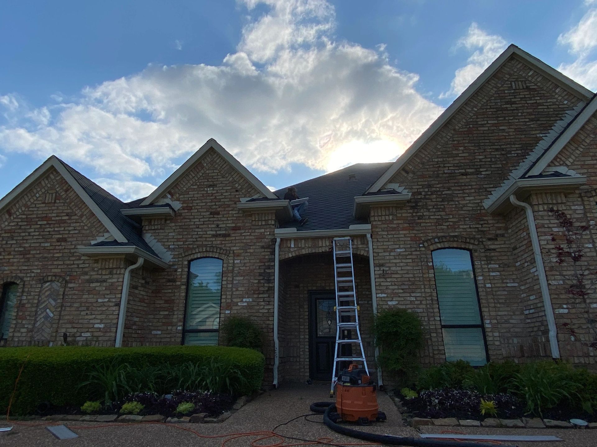A brick house with a ladder sitting in front of it.