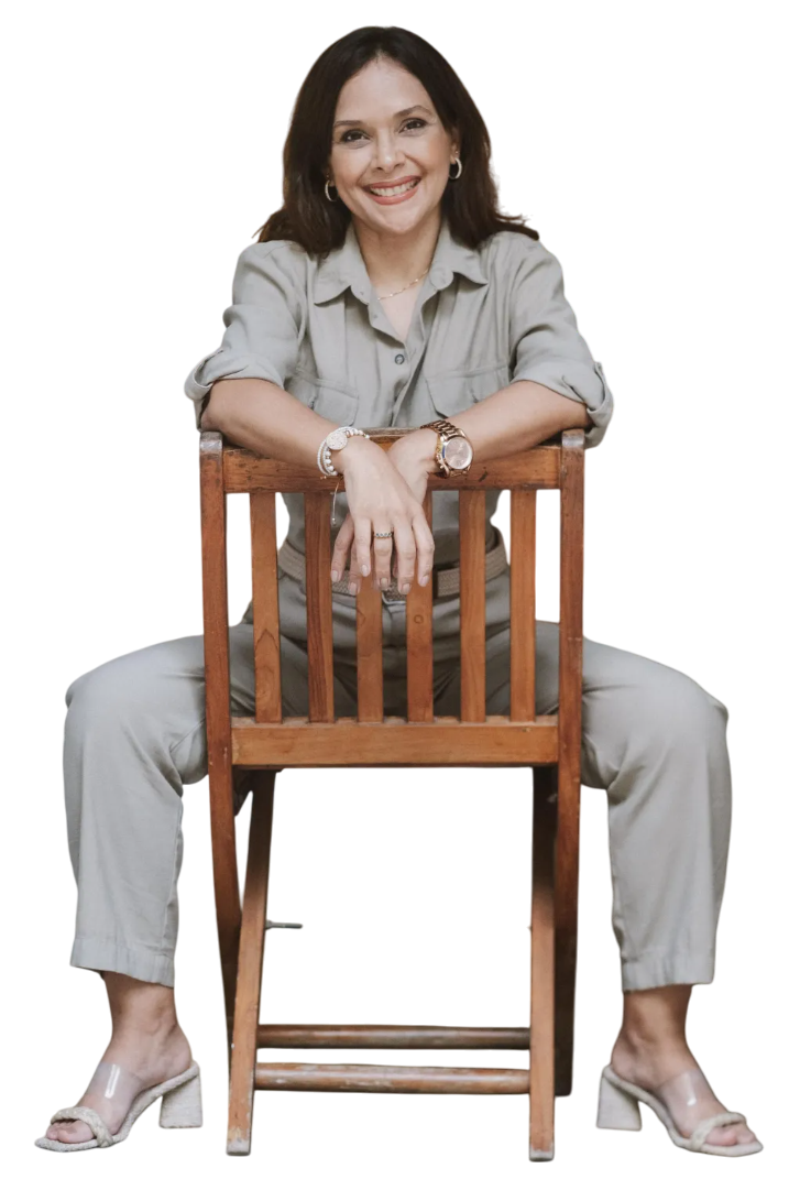 Una mujer está sentada en una silla de madera con las piernas cruzadas.