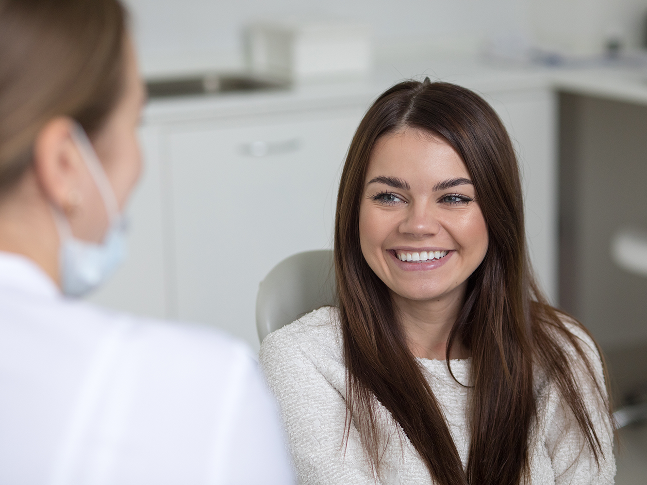 girl sitting in dental chair smiling while talking to dentist staff