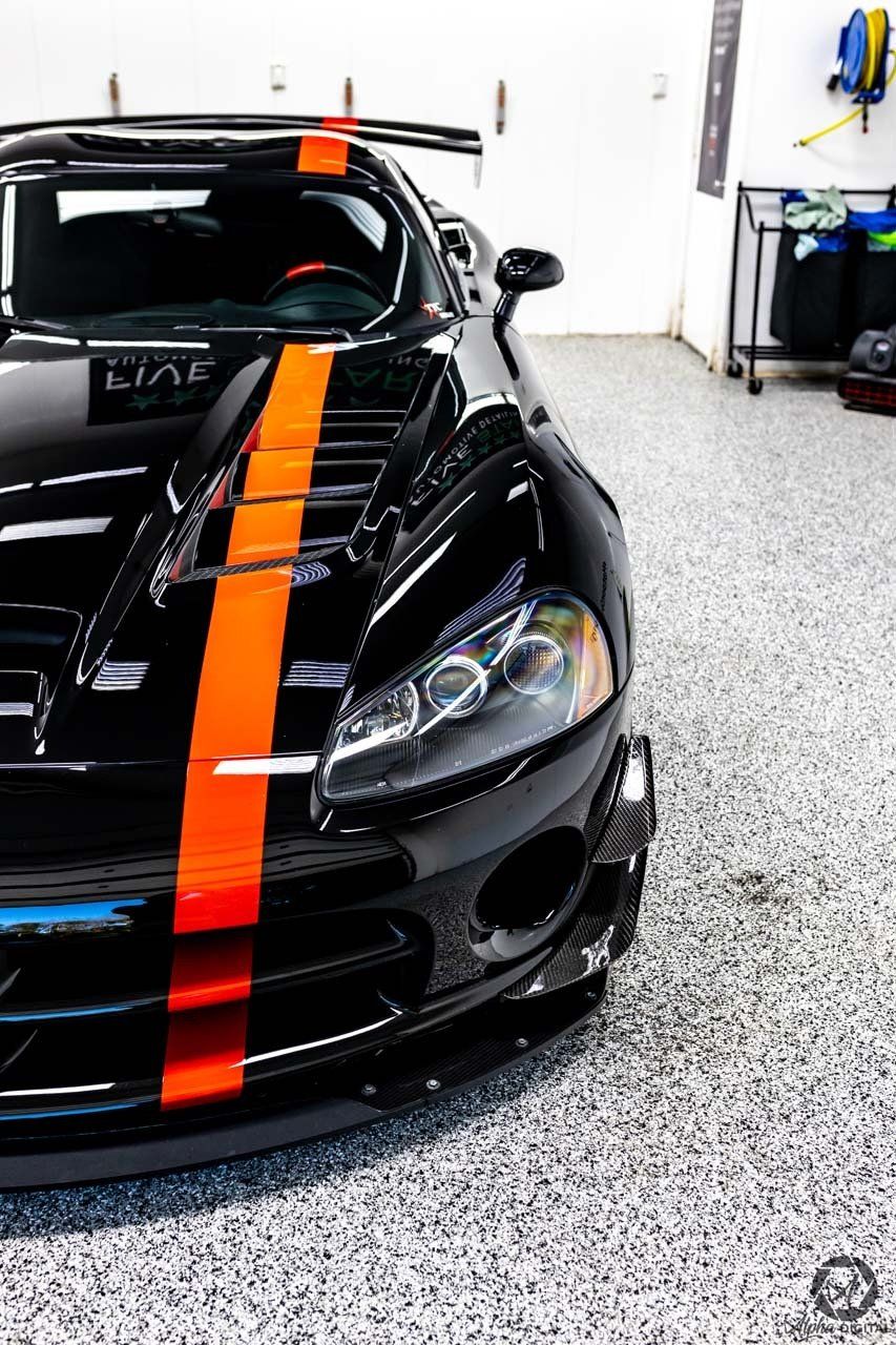A black car with orange stripes is parked in a garage.
