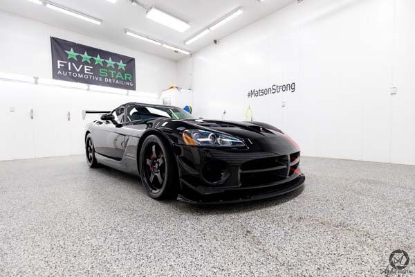 A black dodge viper is parked in a garage.