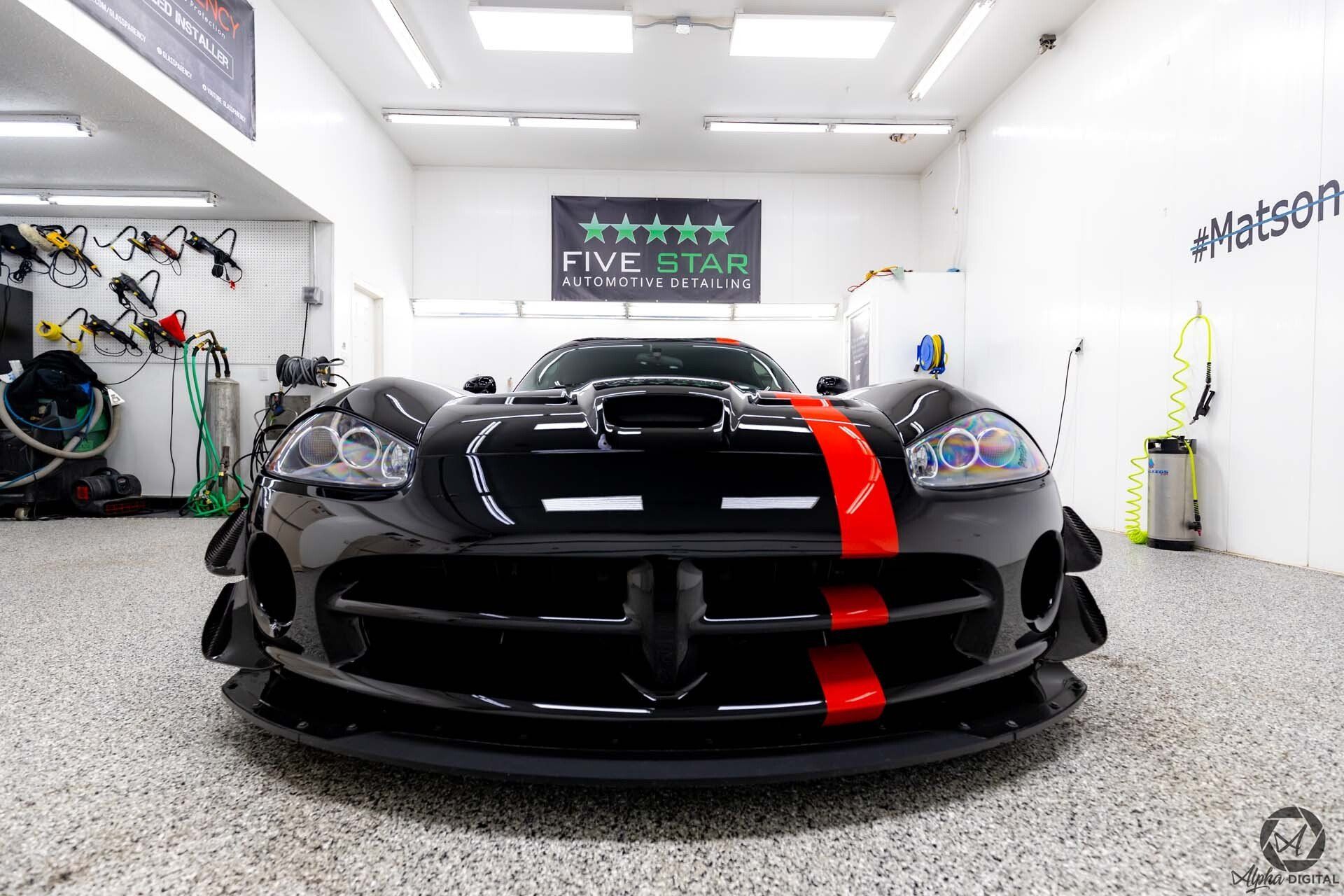 A black and red sports car is parked in a garage.